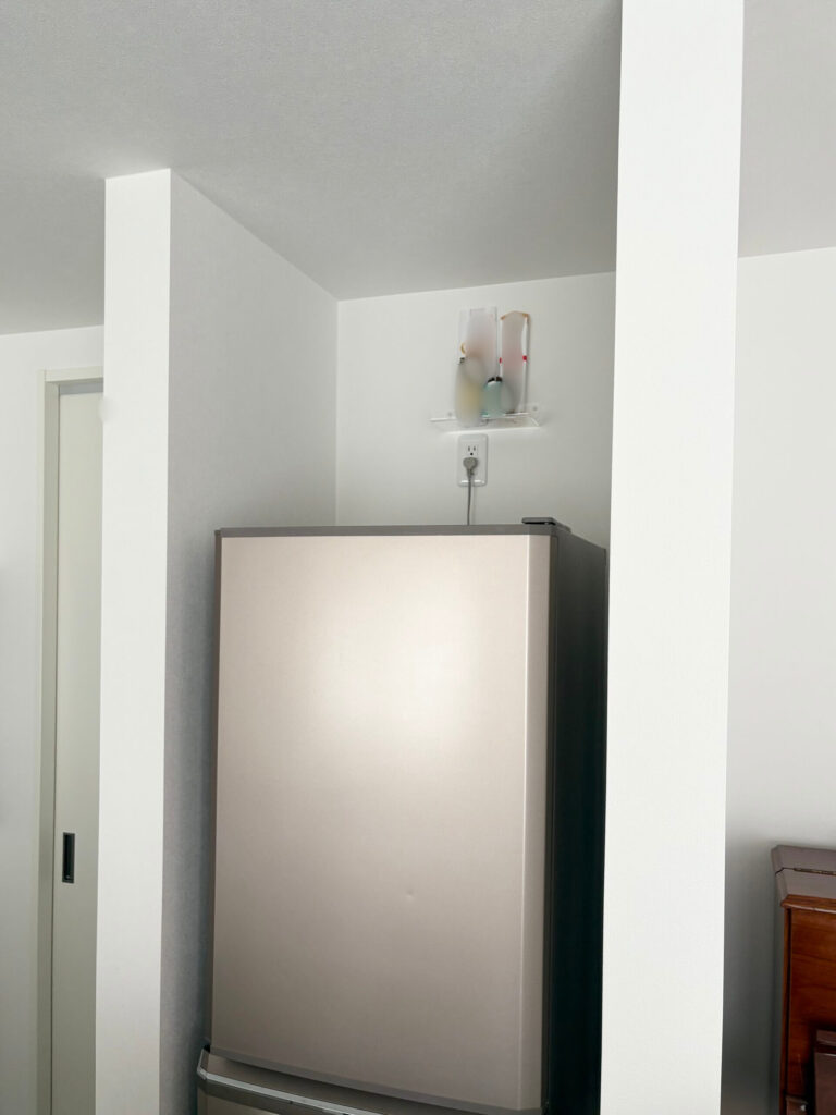 冷蔵庫の上部の壁に無印の「壁に付けられるアクリルディスプレイ」を設置して、神棚としている様子