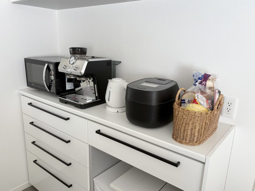 キッチンカウンターの写真。家電が並んでいて、一番端には食品が入ったバスケットが置いてある。