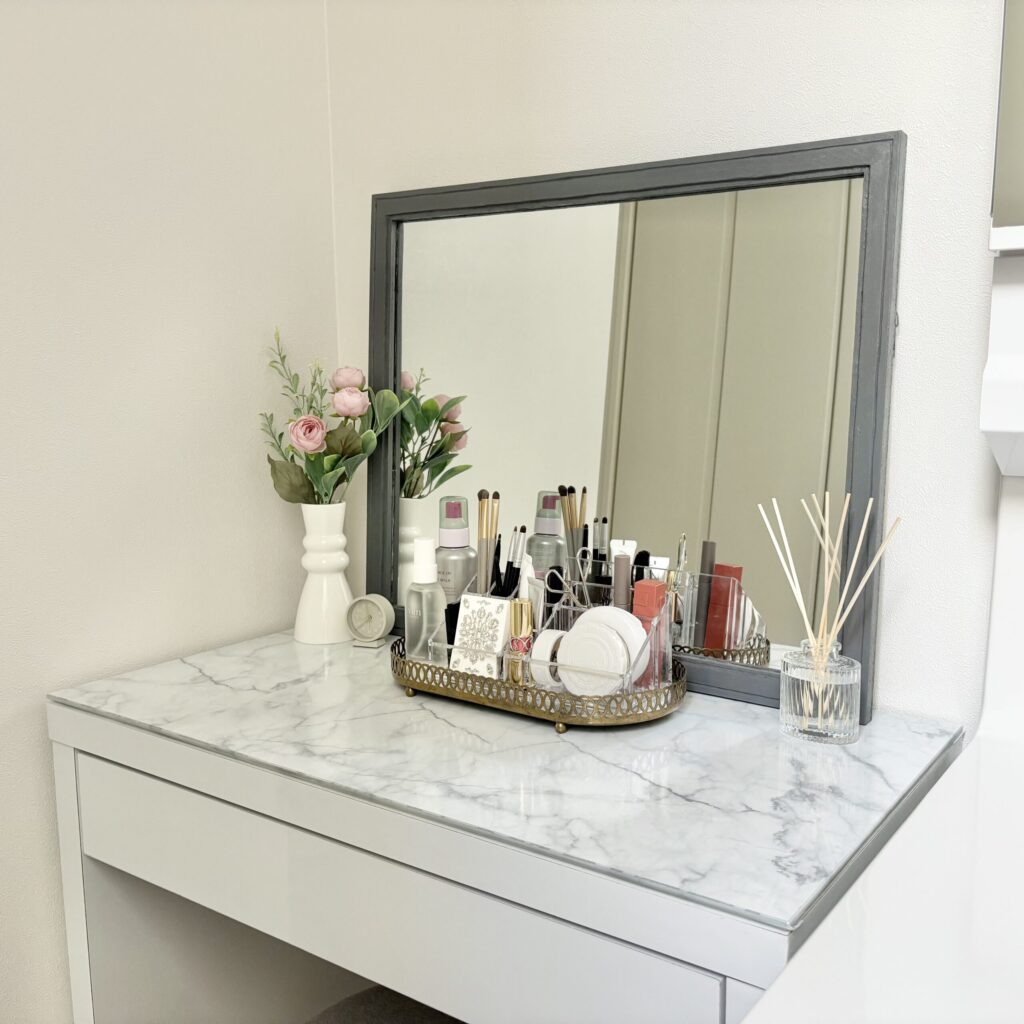 お花屋リードディフューザーが飾られ、きれいに化粧品が並んだメイクスタンドが置かれているドレッサーの写真（斜めから）